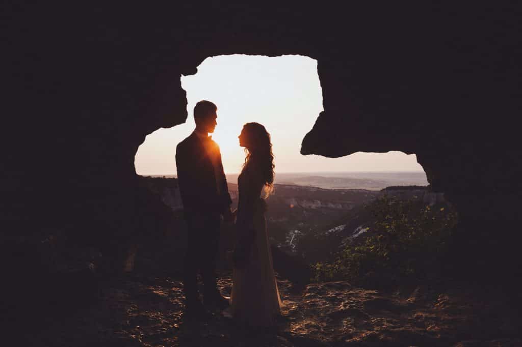 Unusual wedding photography. Sunset in muntains with silhouettes newlyweds